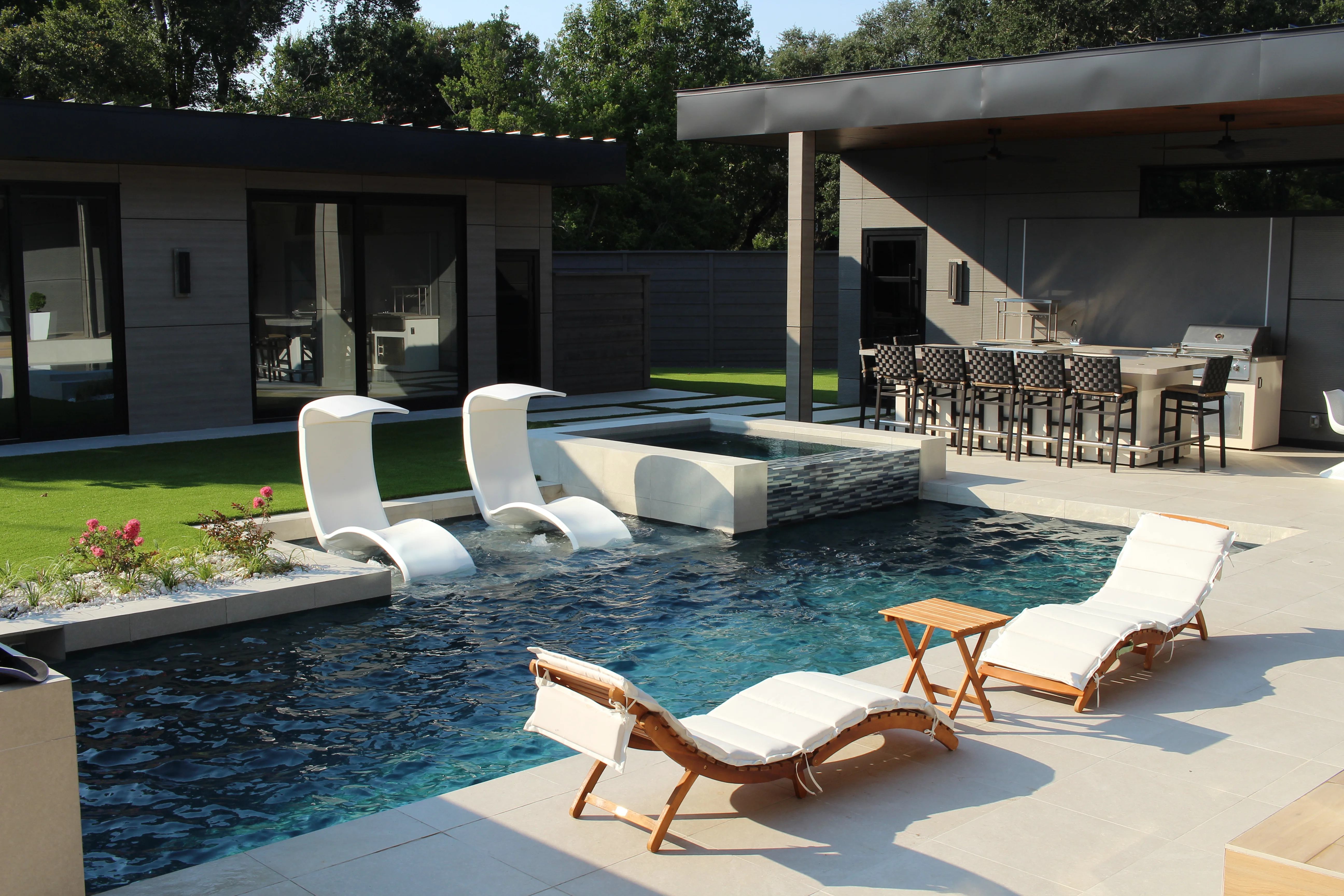 Resort-style swimming pool with spa, white loungers, and modern backyard design